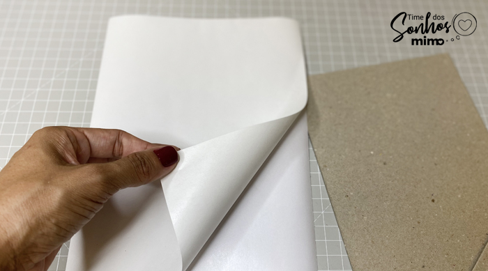 Colando o adesivo holográfico no papelão para capa de receitas