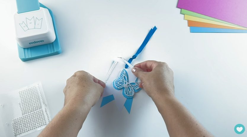 Colando as pérolas com a pinça de precisão nas tags para embalagens