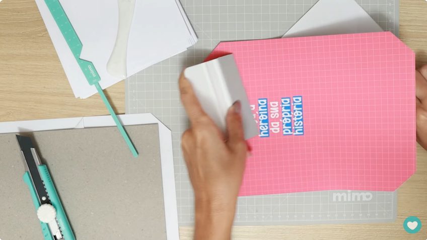 passando a Espátula Mimo para o adesivo aderir bem no papelão
